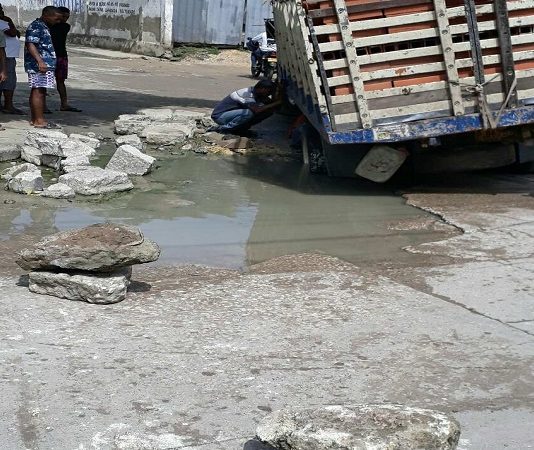 Camión casi volcado al caer en un hueco en una vía del barrio el Pozon